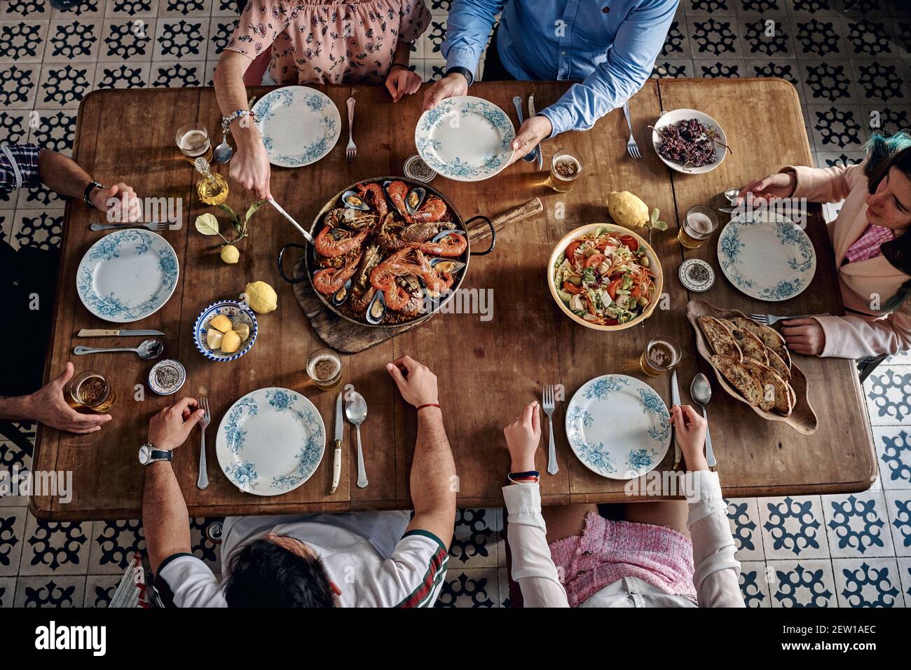 Alto angolo di raccolto irriconoscibile compagnia di amici seduti intorno Tavolo di legno con cibo assortito in ristorante spagnolo e godendo weekend di togethe Foto Stock