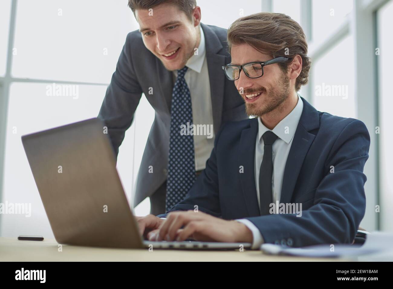 Due imprenditori che lavorano insieme su un progetto seduti ad un tavolo in ufficio Foto Stock