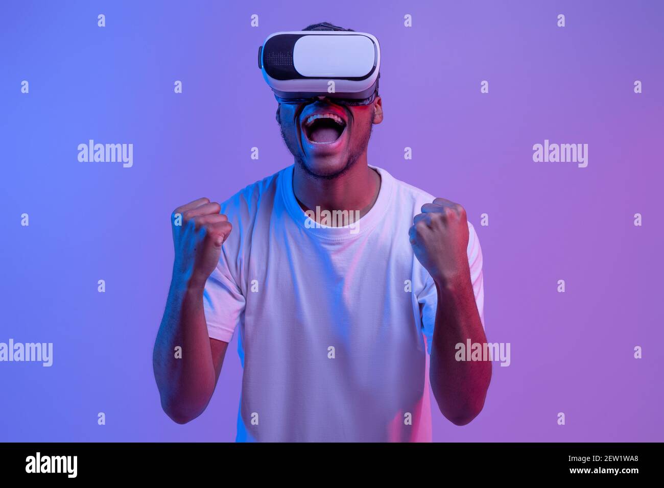 L'uomo afroamericano molto gioioso in VR occhiali che celebrano Win in Videogioco Foto Stock