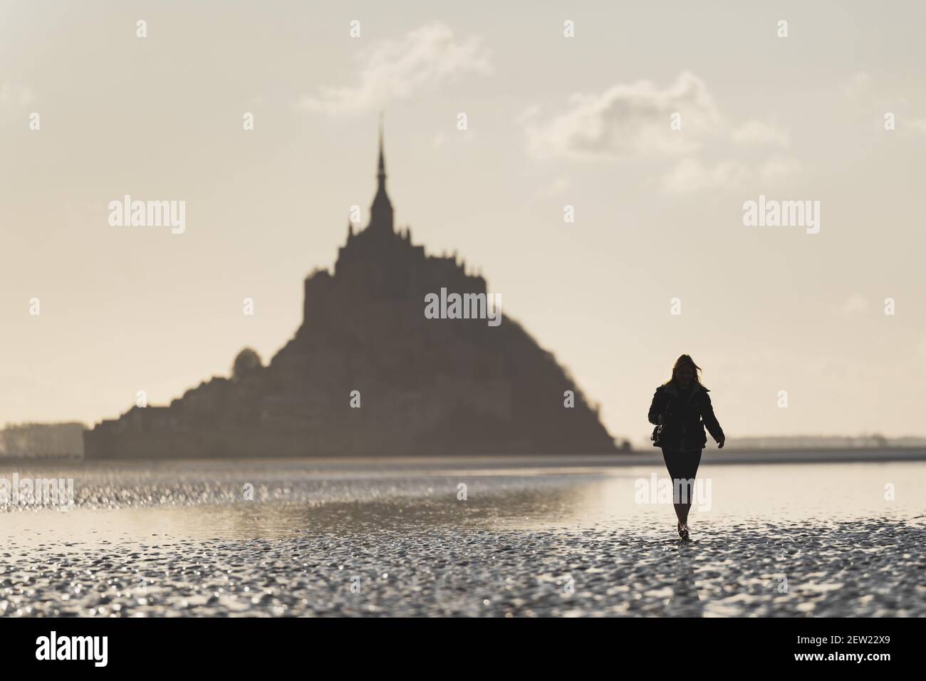 Francia, Manica, il Mont-Saint-Michel, silhouette donna che attraversa la baia di Mont-Saint-Michel Foto Stock