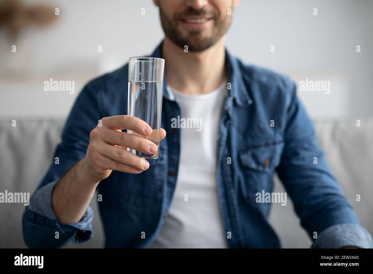 Corto di uomo di mezza età che tiene un bicchiere d'acqua a casa Foto Stock