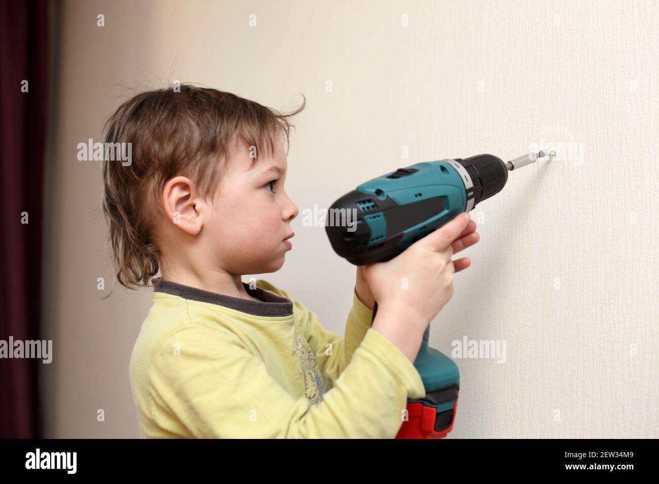Âoy lavorare con cacciaviti cordless a casa Foto Stock