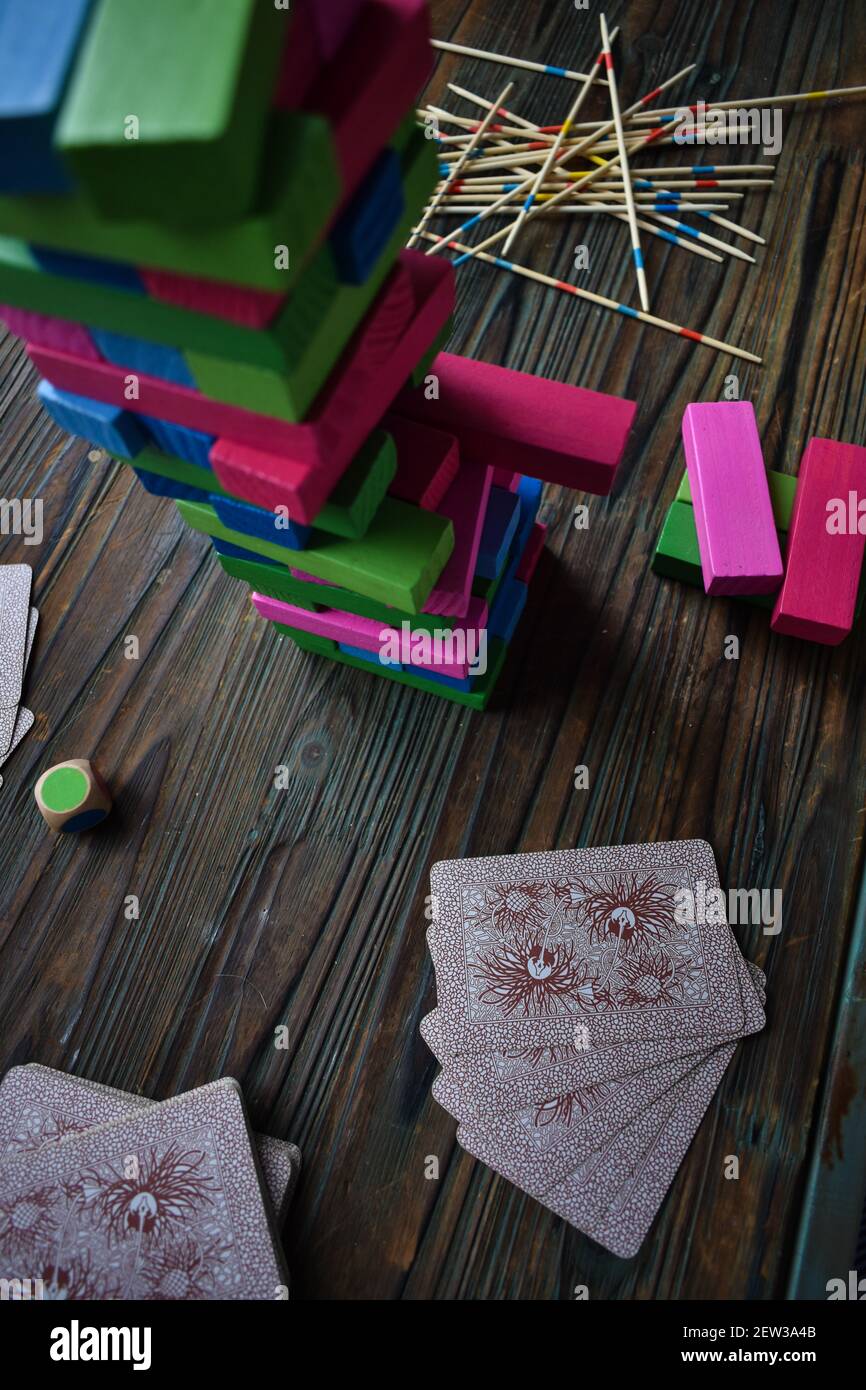 Una vista dall'alto dei colorati blocchi di gioco Jenga impilati l'uno sull'altro, giocando carte e bastoni di legno Foto Stock