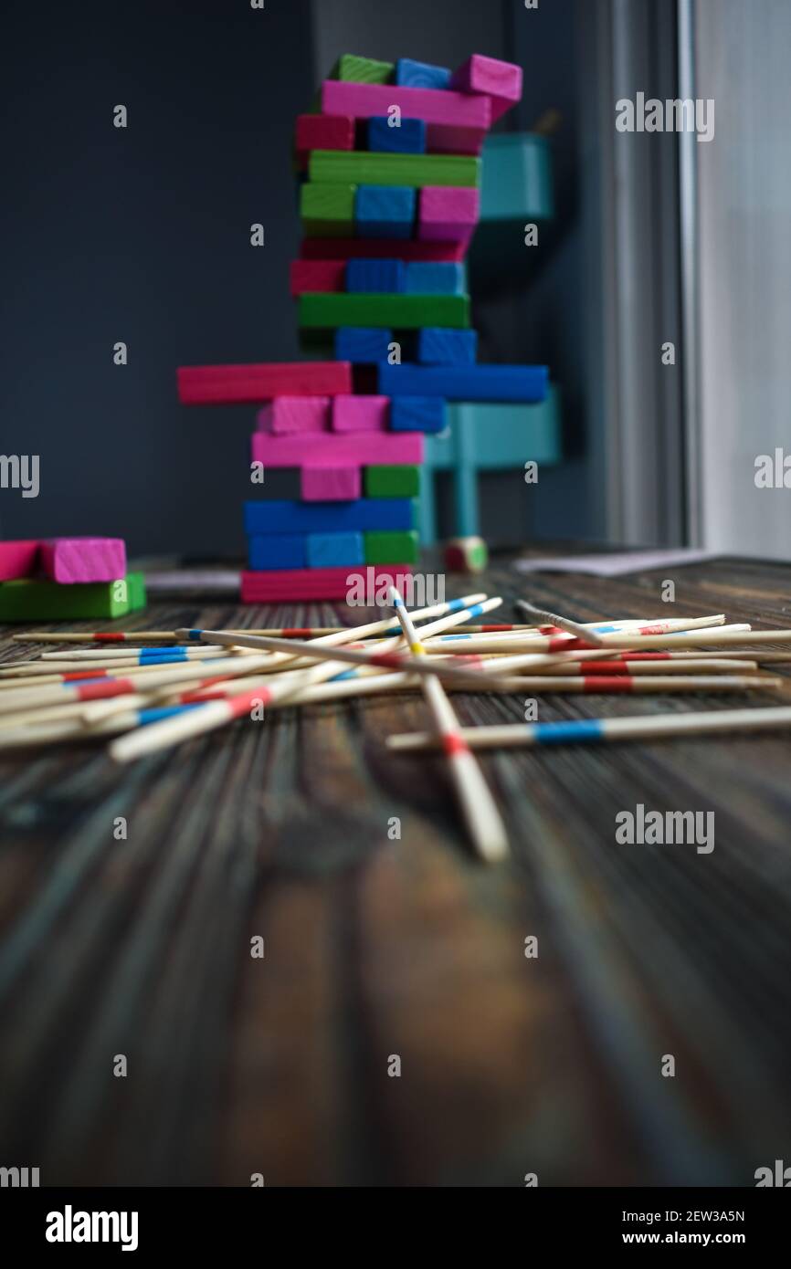 Una foto verticale di blocchi di gioco Jenga colorati accatastati sopra l'un l'altro in primo piano di bastoni di legno Foto Stock