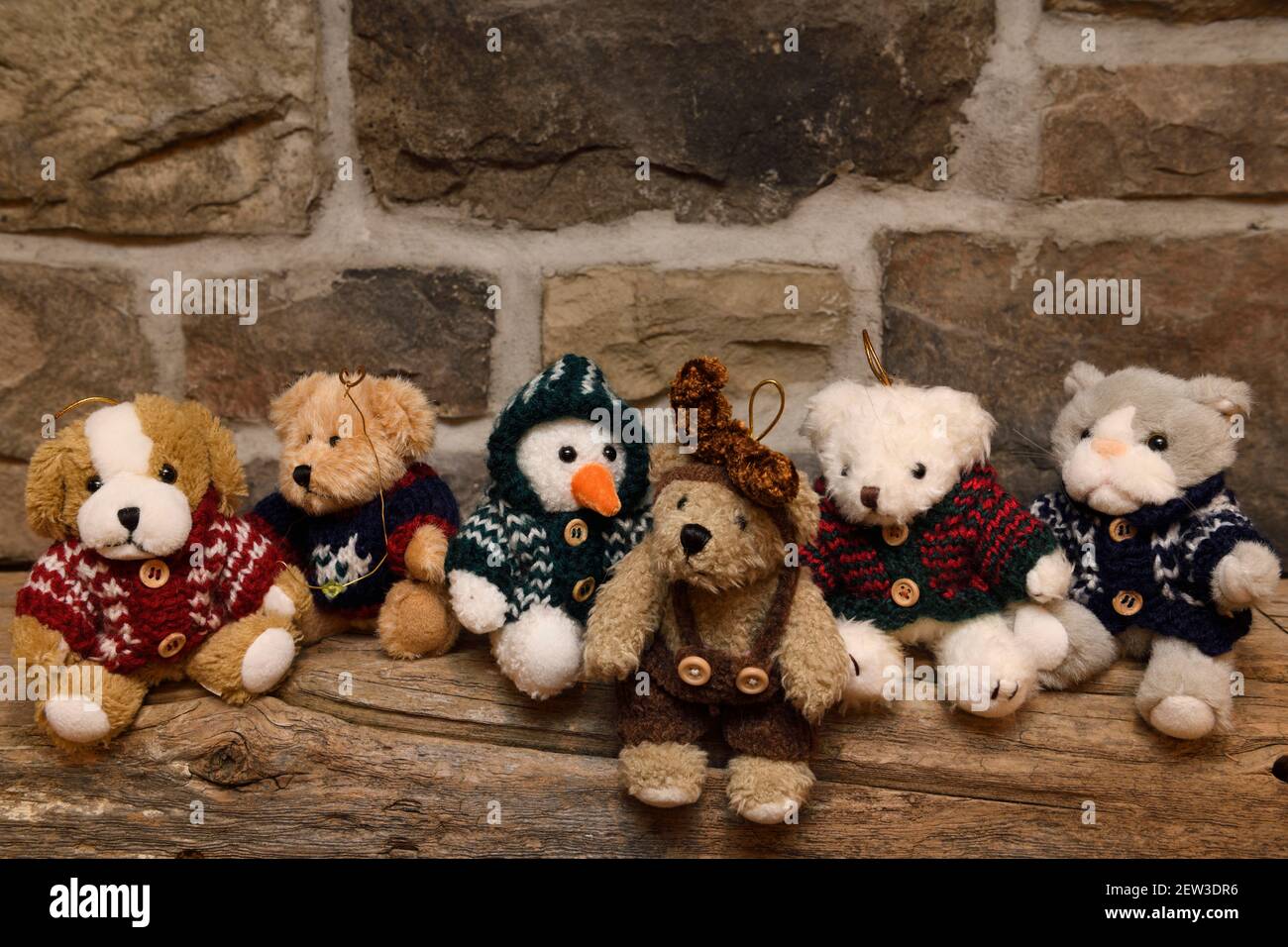 Giocattoli di orsacchiotti e cani imbottiti con pelucchi a maglia sul mantel del fascio del fienile su camino di pietra Foto Stock