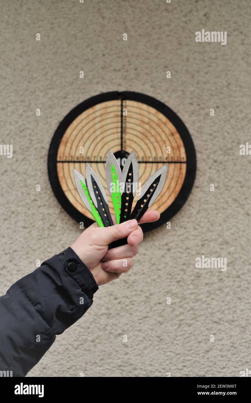 Lancio di coltelli. Sport e hobby . Lancio coltelli in una mano dell'uomo e un bersaglio sulla wall.Outdoor sport. Concetto di raggiungimento degli obiettivi. Foto Stock