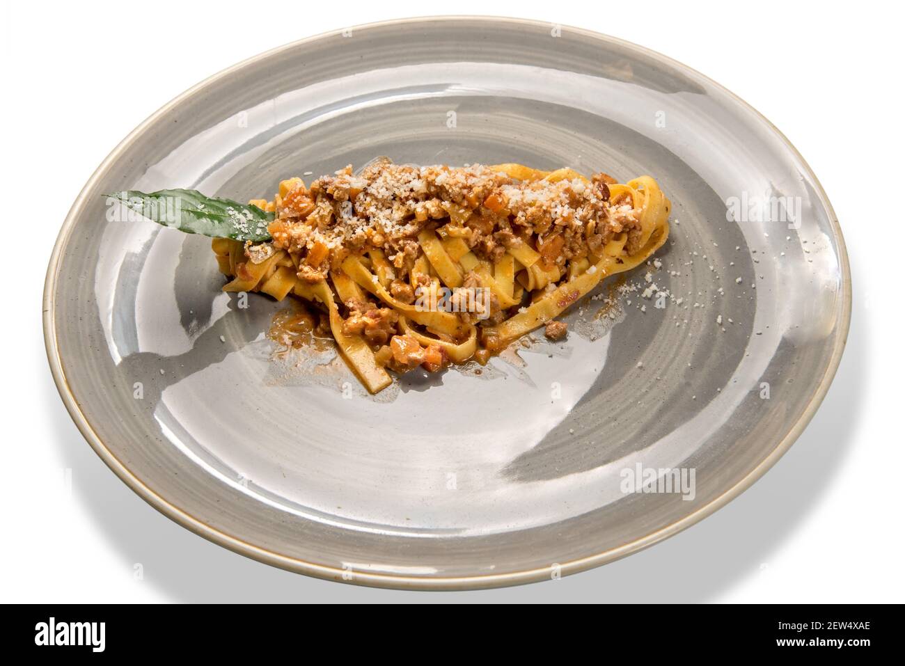 Tagliatelle al ragù Bolognese e parmigiano grattugiato. Pasta all'uovo con salsa di carne bolognese in piatto rustico isolato sul bianco Foto Stock
