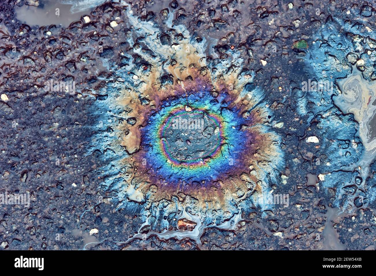 L'olio gocciola dal motore dell'auto sulla strada e si è rivelato un punto di sole arcobaleno. Inquinamento ambientale. Foto Stock