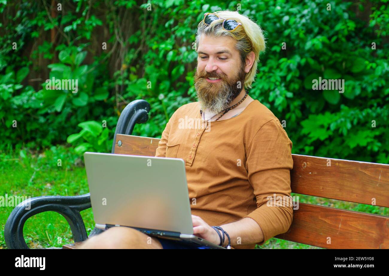 Uomo sopportato lavoratore freelance. Processo remoto. Uomo sorridente che lavora su un computer portatile. Studiare e lavorare online. Foto Stock