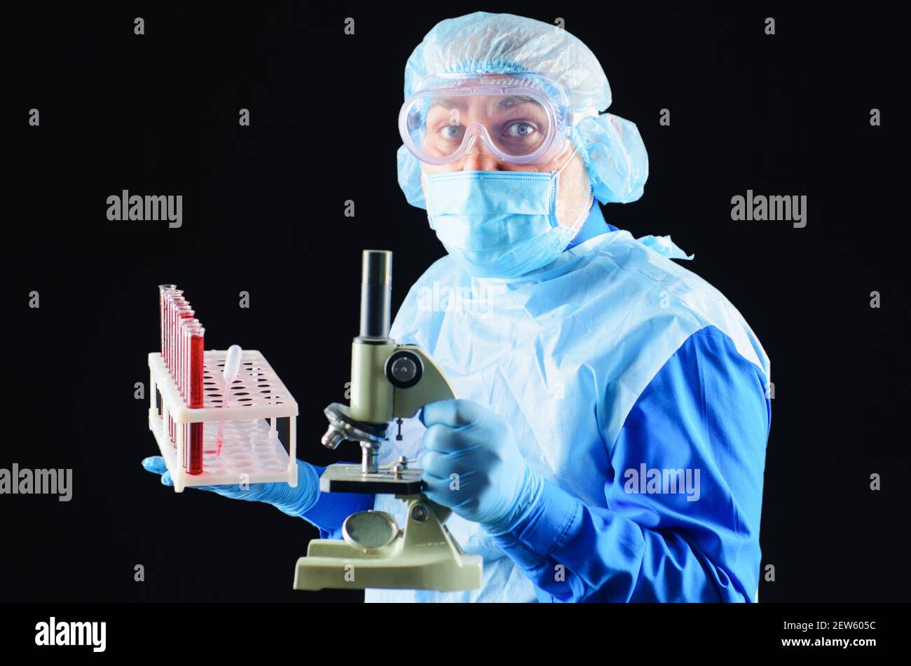 Medico con provette per analisi del sangue e microscopio. Tecnico di laboratorio che analizza il campione di sangue. Scienza e medicina. Foto Stock