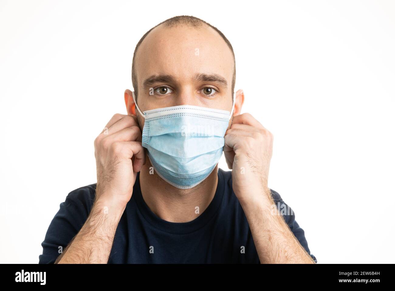 Un maschio bianco caucasico che indossa una maglietta blu e indossa una maschera chirurgica blu. Foto Stock