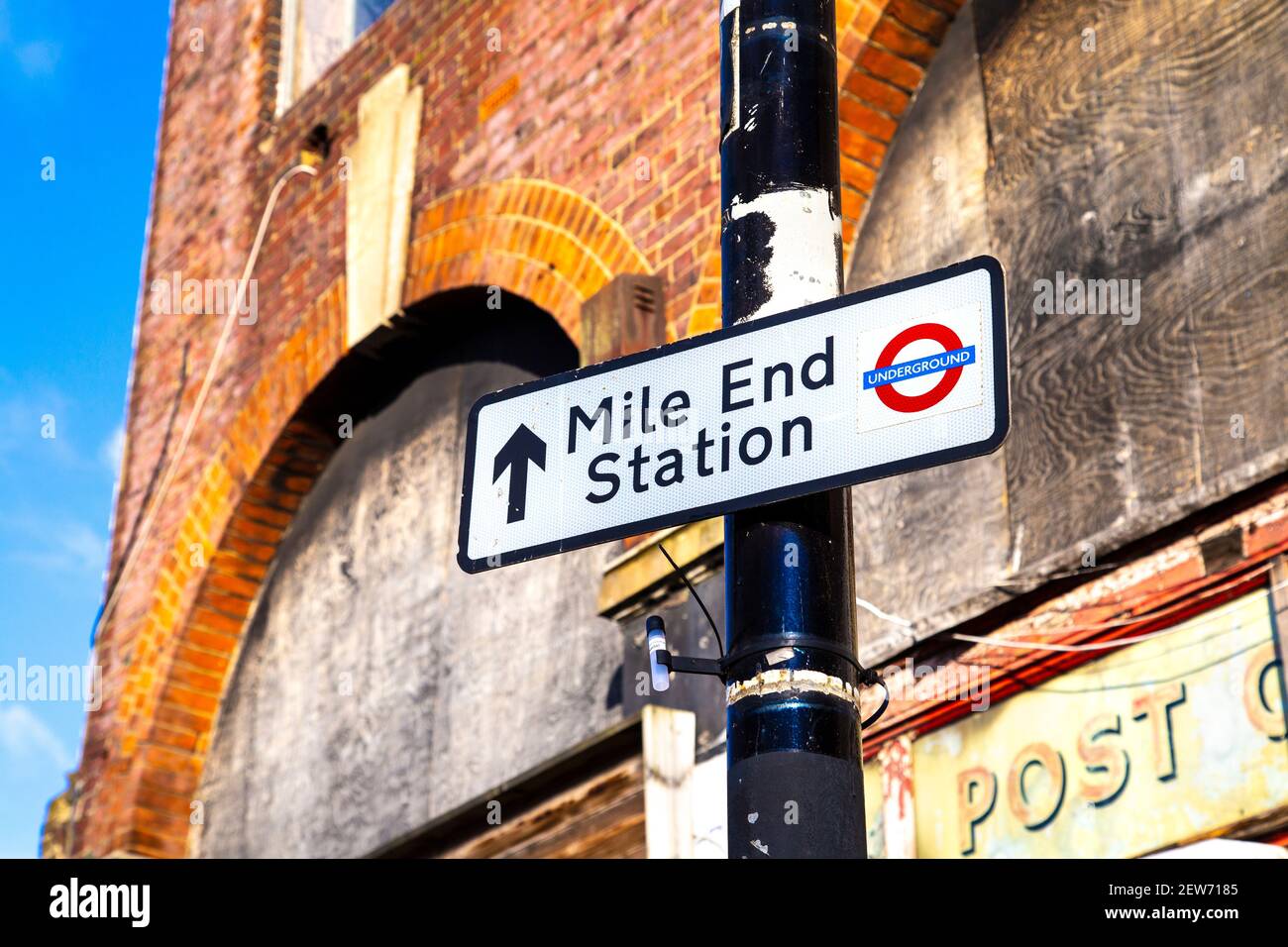 Cartello della stazione della metropolitana Mile End di fronte a un ex edificio dell'ufficio postale, Tower Hamlets, Londra, Regno Unito Foto Stock