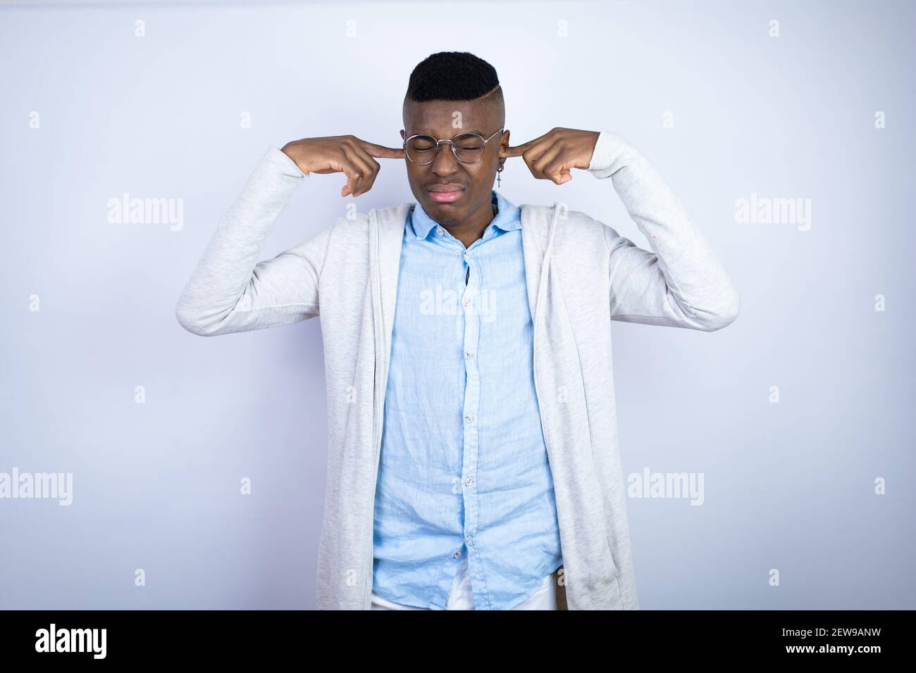 Giovane bell'uomo afroamericano che indossa abiti casual che coprono le orecchie con le dita con un'espressione seccata per il rumore della musica forte. Sordo concep Foto Stock