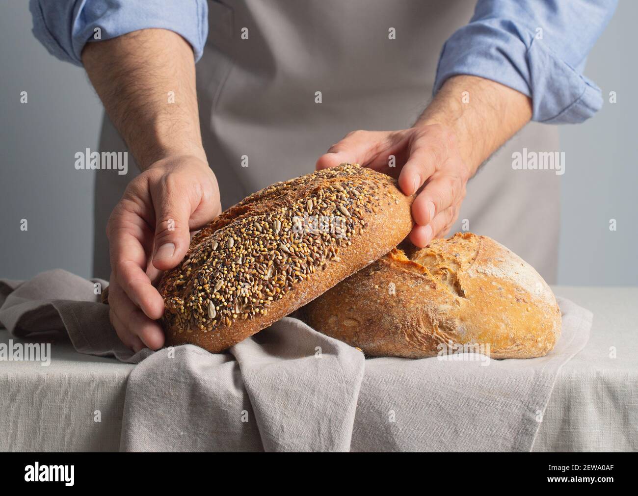 Baker che tiene il pane appena sfornato con le mani, primo piano Foto Stock