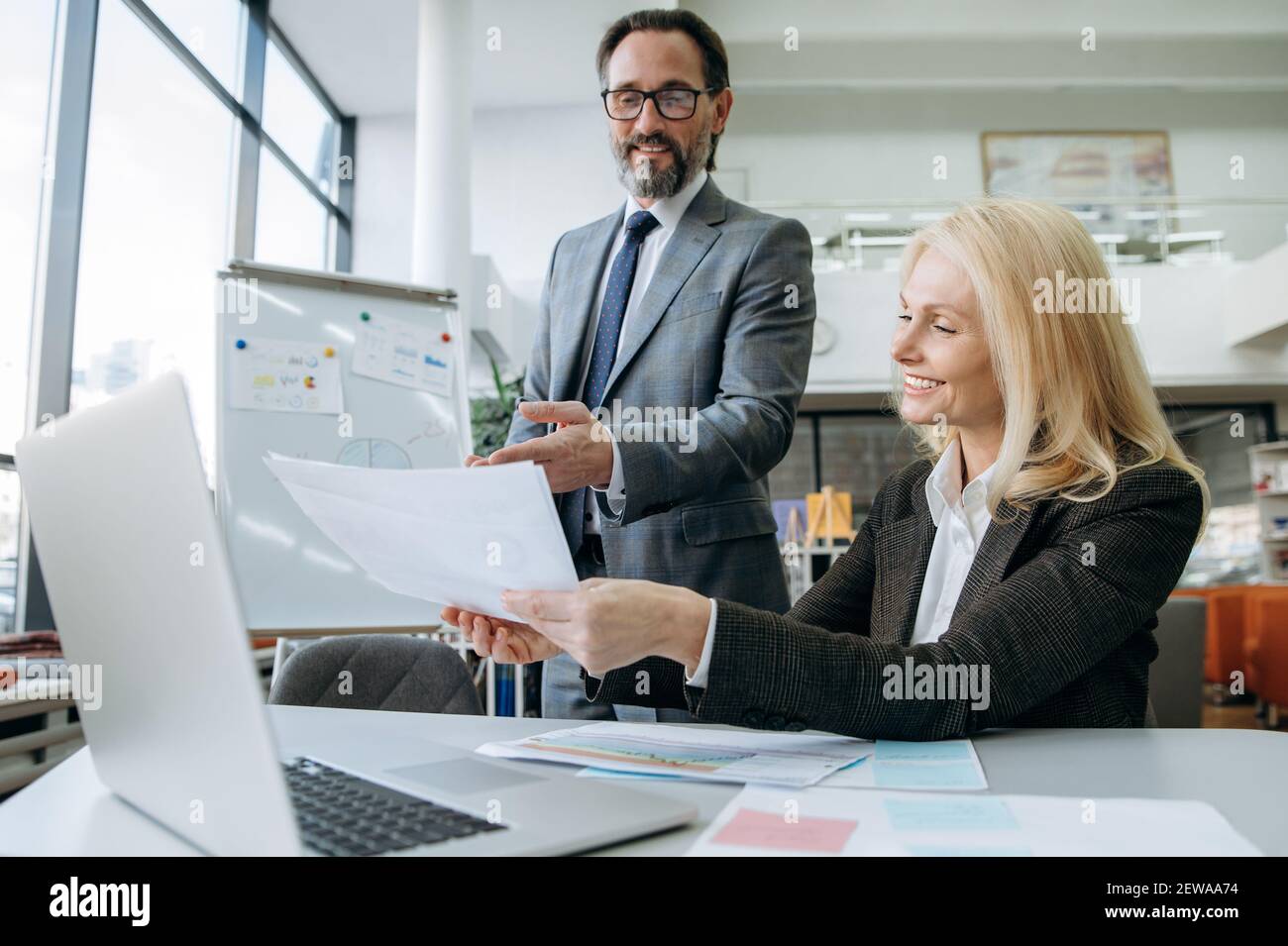 Colleghi senior di successo che sviluppano un nuovo progetto, discutendo di idee. Bella donna bionda-capelli che lavora su business plan insieme con attraente collega uomo Foto Stock