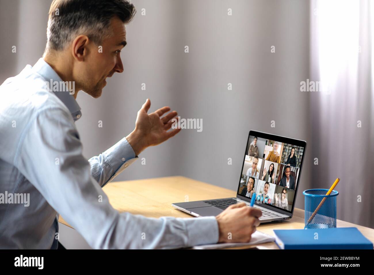 Un uomo adulto di successo usa un laptop per la comunicazione video con i partner commerciali. Un manager o ceo è seduto alla sua scrivania, sta parlando con i colleghi in videochiamata, i dipendenti di successo sono sul Foto Stock
