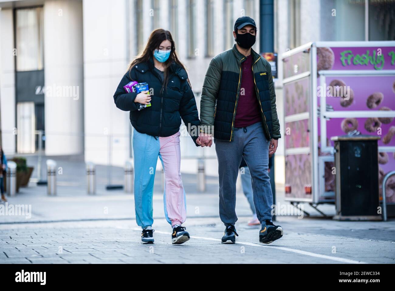 Coppia interrazziale che tiene le mani mentre fuori a piedi durante il blocco covid a Birmingham, Regno Unito Foto Stock