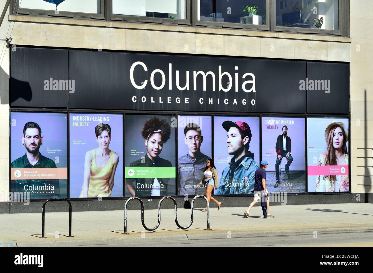 Chicago, Illinois, Stati Uniti. Pedoni su Michigan Avenue da grandi poster che identificano uno degli edifici che definiscono il campus del Columbia College. Foto Stock