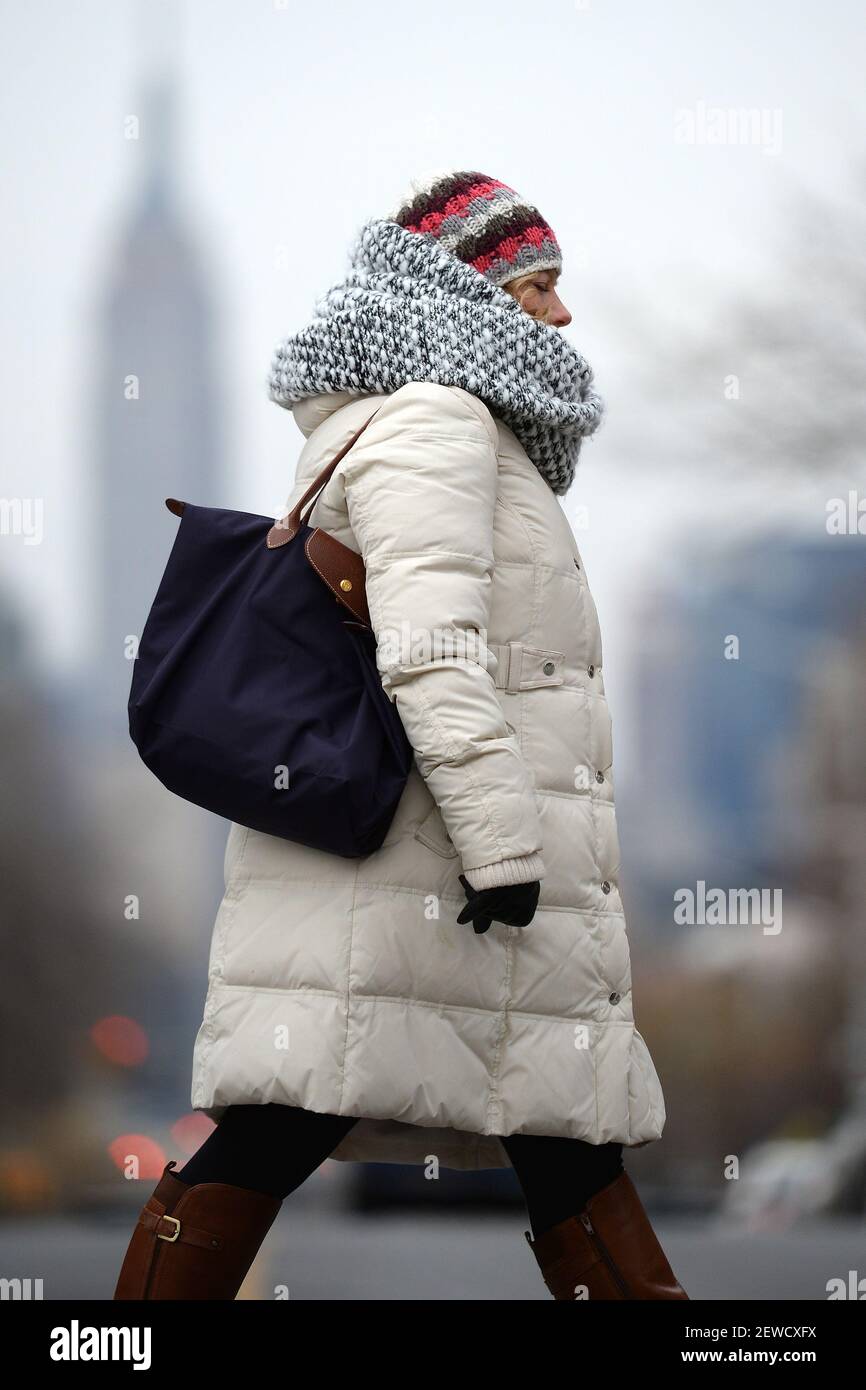 Una donna che indossa uno spesso cappotto invernale e una sciarpa pesante  attraversa 47th Avenue nella sezione Sunnyside di Queens, mentre le  temperature scendono sotto il congelamento a New York, NY, il