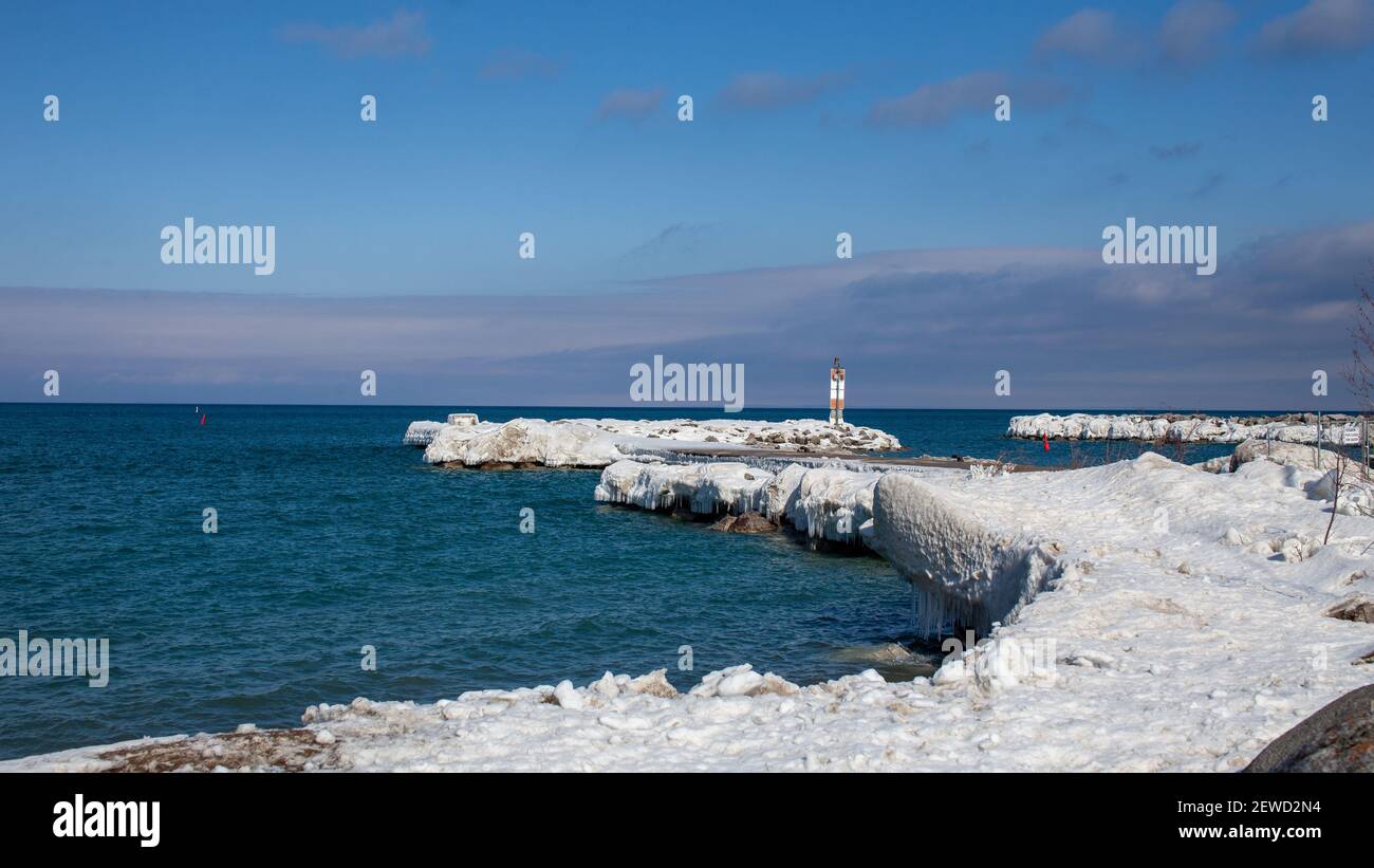 Il molo ghiacciato all'entrata del porto turistico Thornbury Yacht Club in inverno. Grandi falde di ghiaccio appendono dal litorale dopo le tempeste invernali p Foto Stock