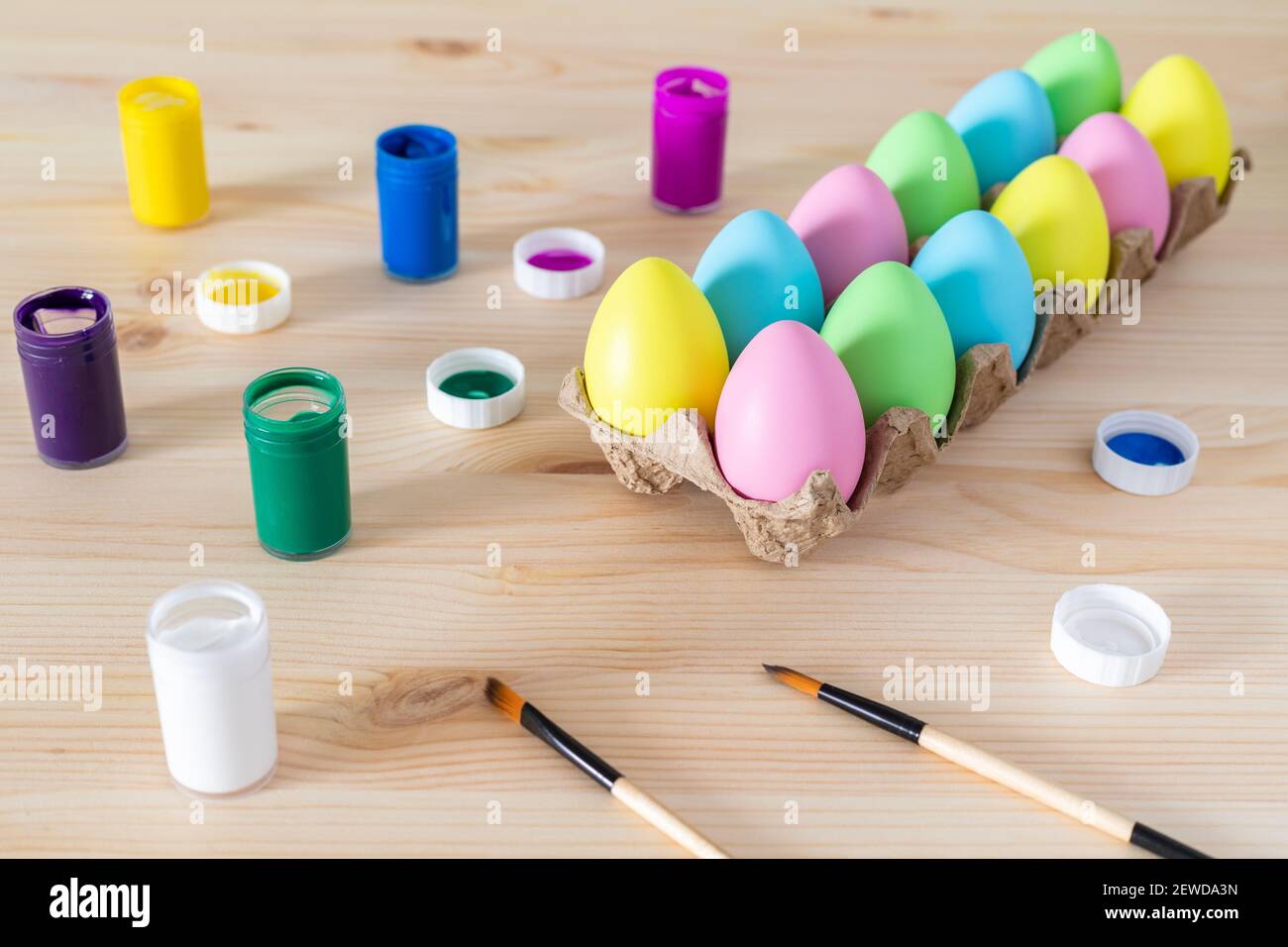 Uova di Pasqua e pitture colorate con pennelli sul tavolo. Concetto di artigianato pasquale. Foto Stock
