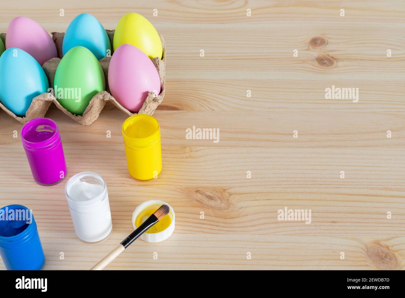 Uova di Pasqua e pitture colorate con pennelli sul tavolo. Concetto di artigianato pasquale. Foto Stock