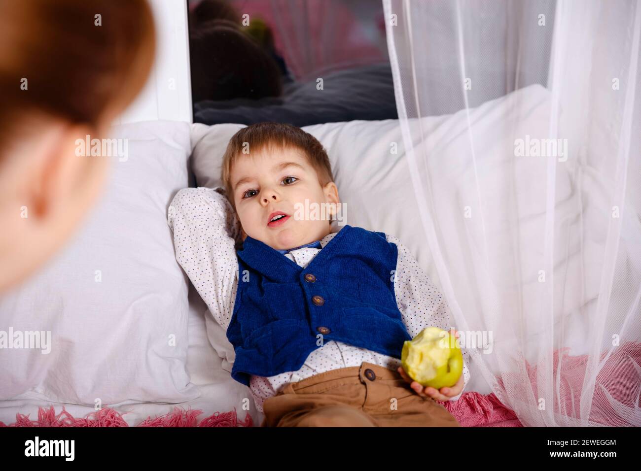 Mummia che controlla il figlio malato che si trova a letto. Mothercare per un bambino malato. Foto Stock