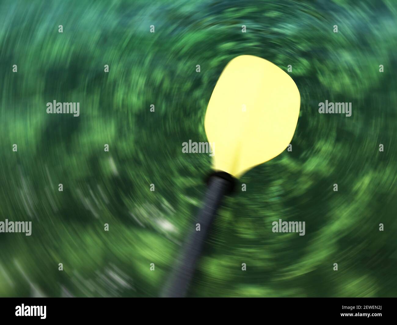 Lama gialla sfocata della pala dell'imbarcazione. Sfocatura del movimento radiale dello sfondo primario verde scuro con colori verdognoli chiari. Foto Stock