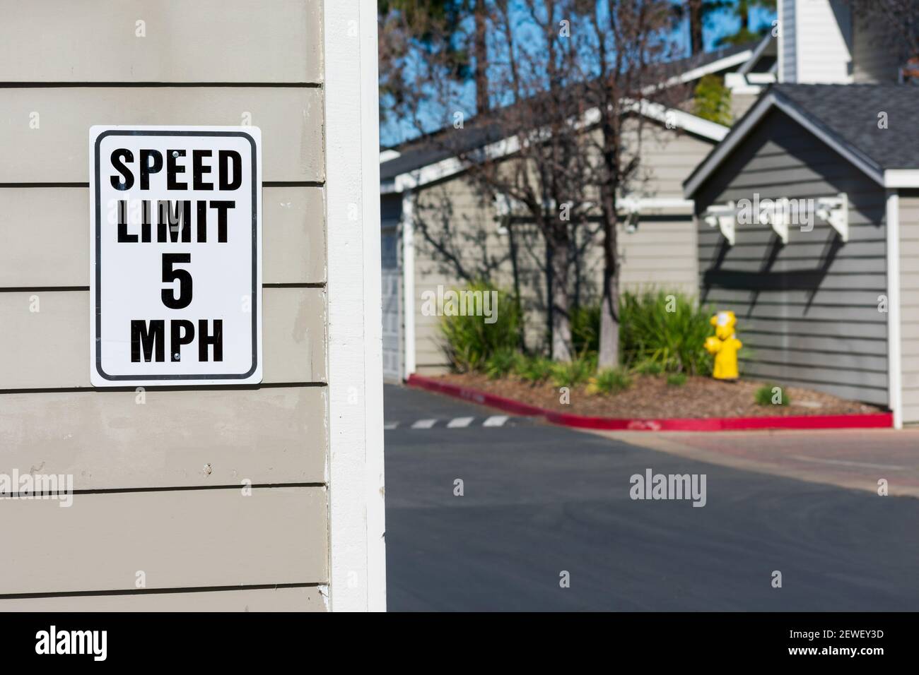 segnale del limite di velocità di 5 mph in aree residenziali. Vialetto sfocato in un complesso residenziale. Foto Stock