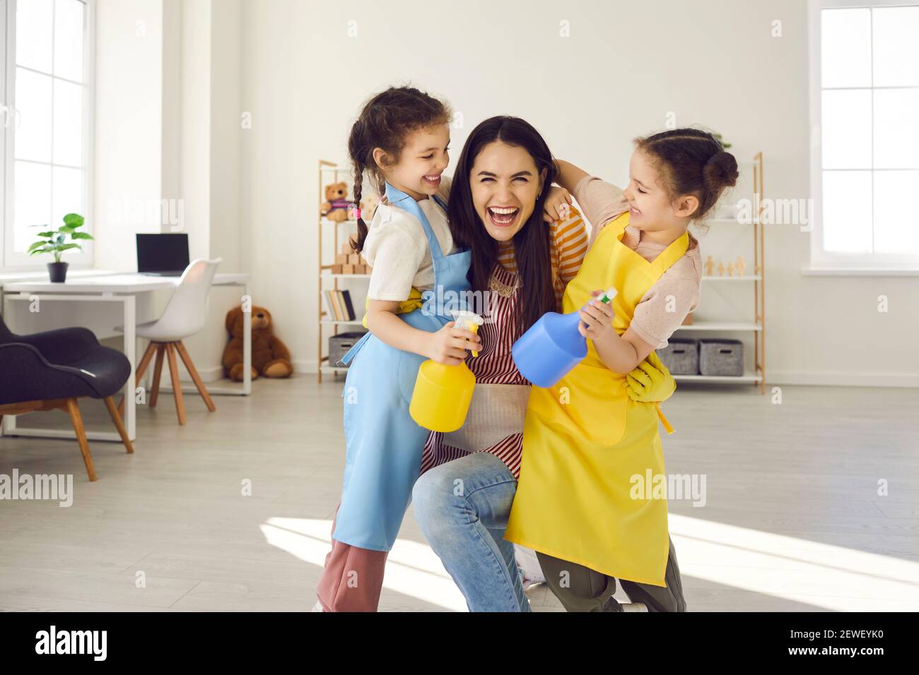 Madre con due figlie che si divertono e si fooling intorno durante la pulizia della casa. Foto Stock