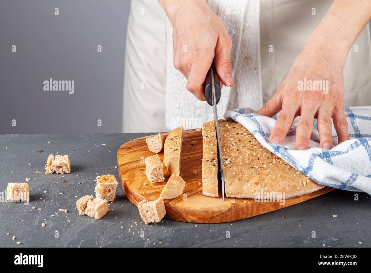 Una chef donna sta affettando pane turco piatto appena sfornato, conosciuto come pide o pita, su un tagliere di legno. Il pane integrale pita è rotondo wit Foto Stock