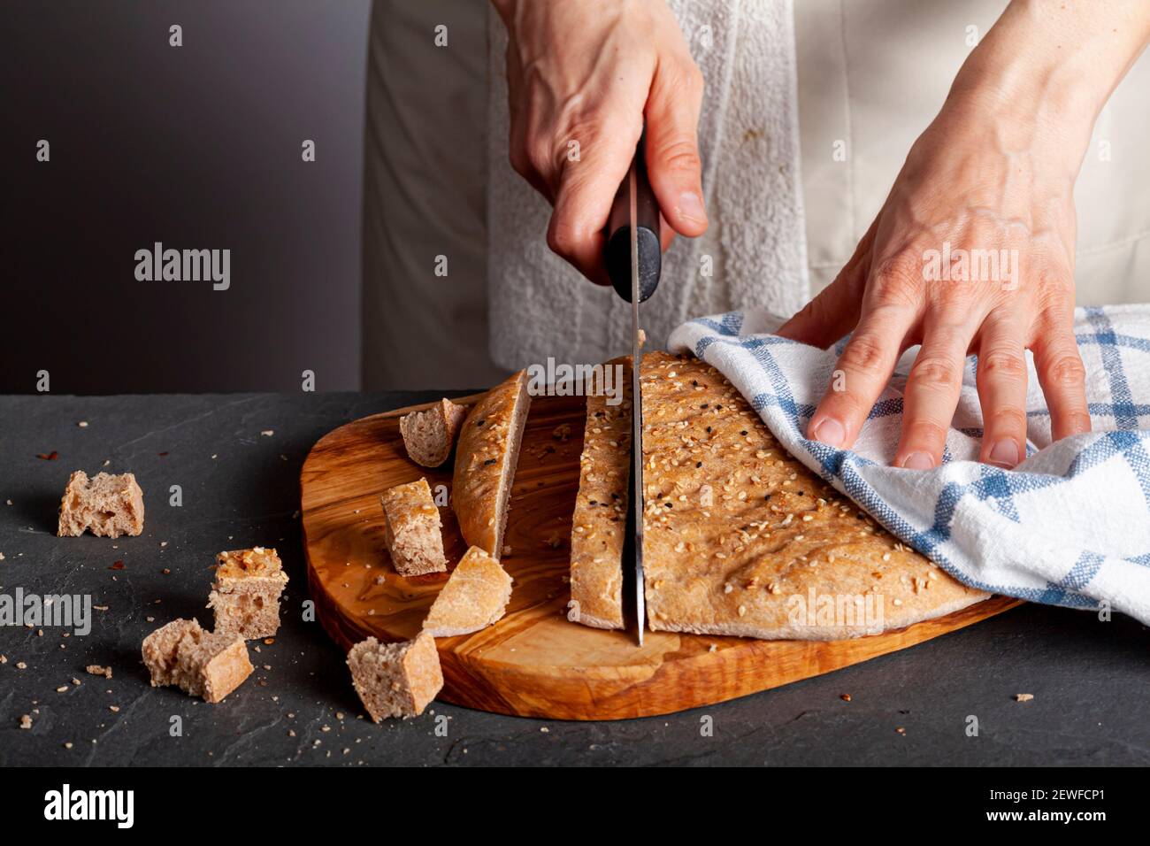 Una chef donna sta affettando pane turco piatto appena sfornato, conosciuto come pide o pita, su un tagliere di legno. Il pane integrale pita è rotondo wit Foto Stock