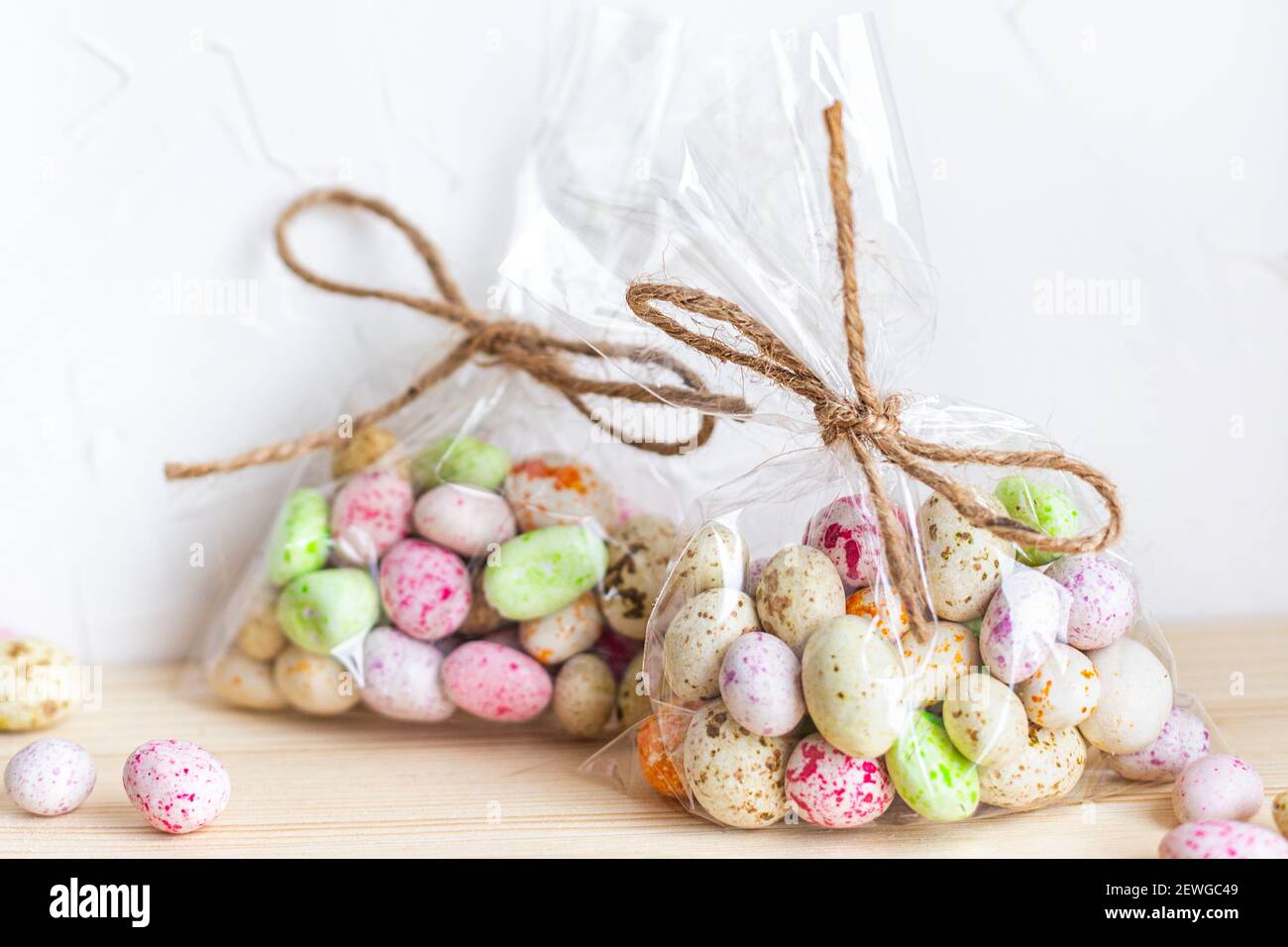 Uova di Pasqua, caramelle in smalto colorato in sacchetti trasparenti su sfondo chiaro Foto Stock