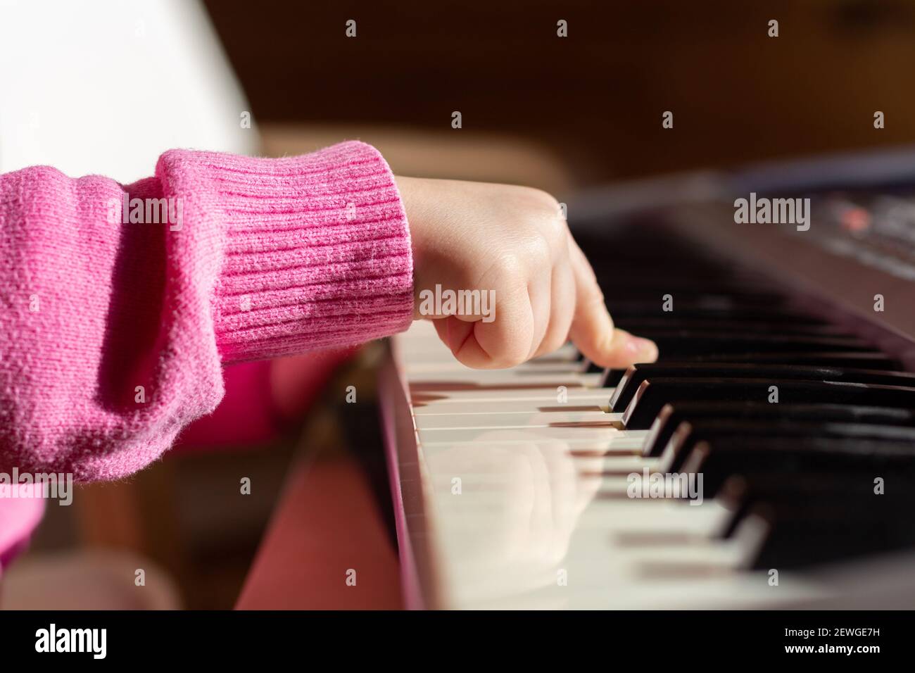 Primo piano della mano del bambino sui tasti del pianoforte o del sintetizzatore, vista laterale. Foto Stock