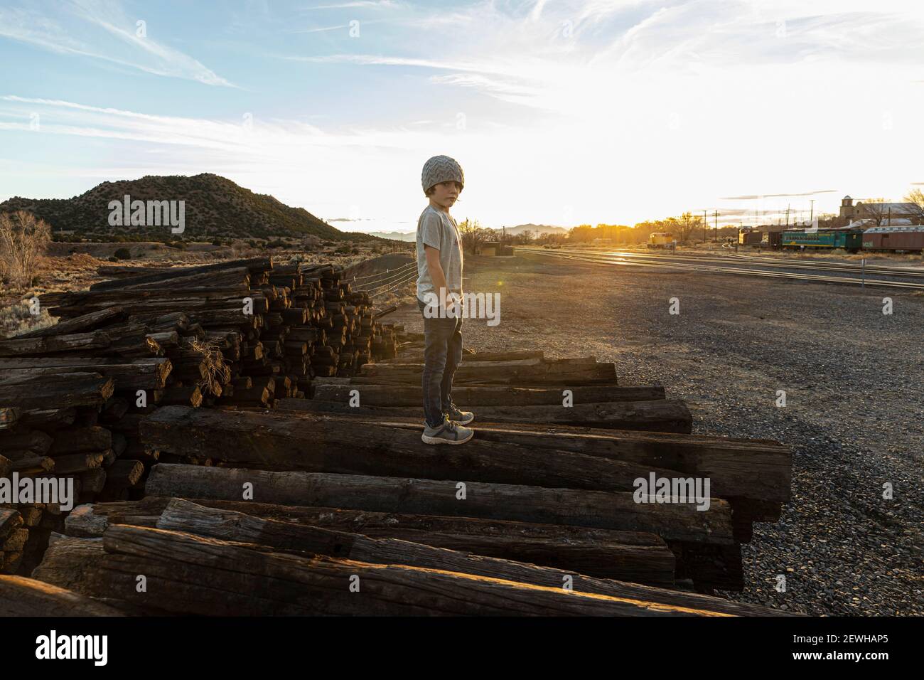 ragazzo di 7 anni in piedi da solo sulle cravatte ferroviarie a. tramonto Foto Stock