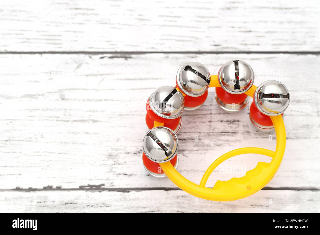 campana colorata di jingle su un tavolo di legno bianco Foto Stock