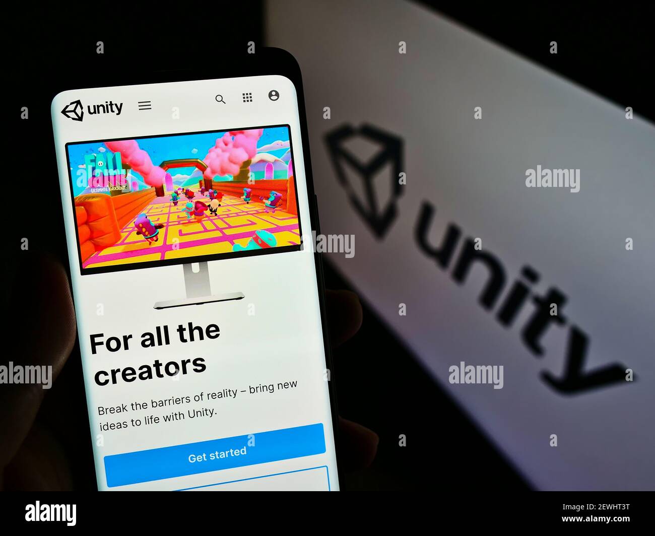 Persona che tiene il cellulare con la pagina web della società americana di videogiochi Unity Software Inc sullo schermo di fronte al logo. Mettere a fuoco il centro del display del telefono. Foto Stock