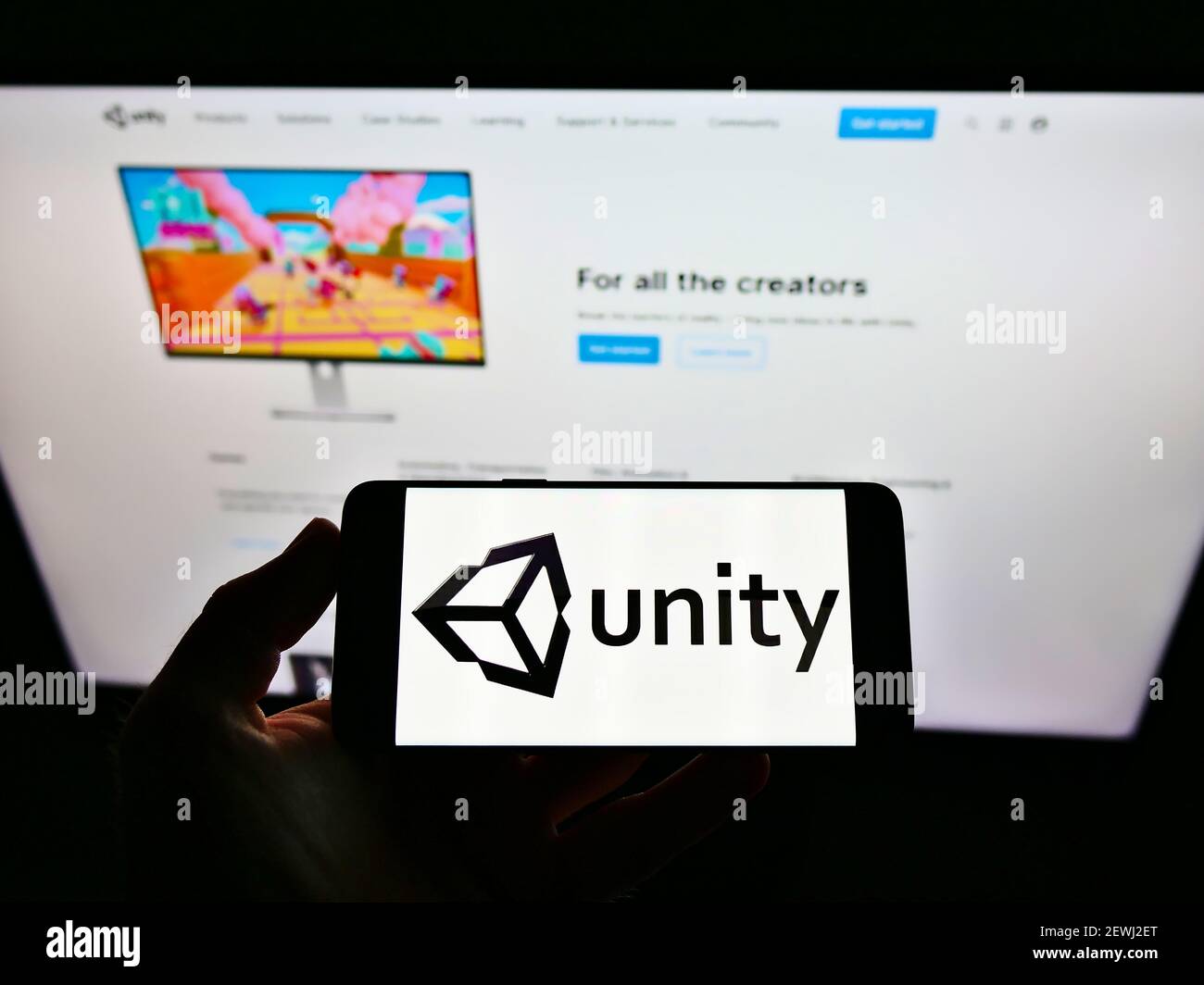 Persona che tiene lo smartphone con il logo della società di videogiochi statunitense Unity Software Inc. Sullo schermo davanti al sito Web. Mettere a fuoco il display del telefono. Foto Stock
