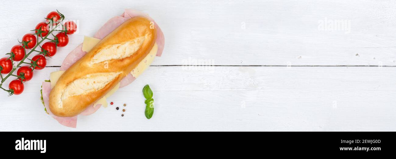 Sub sandwich baguette con prosciutto e formaggio copyspace copyspace banner da sopra banner su legno di tavola. Foto Stock