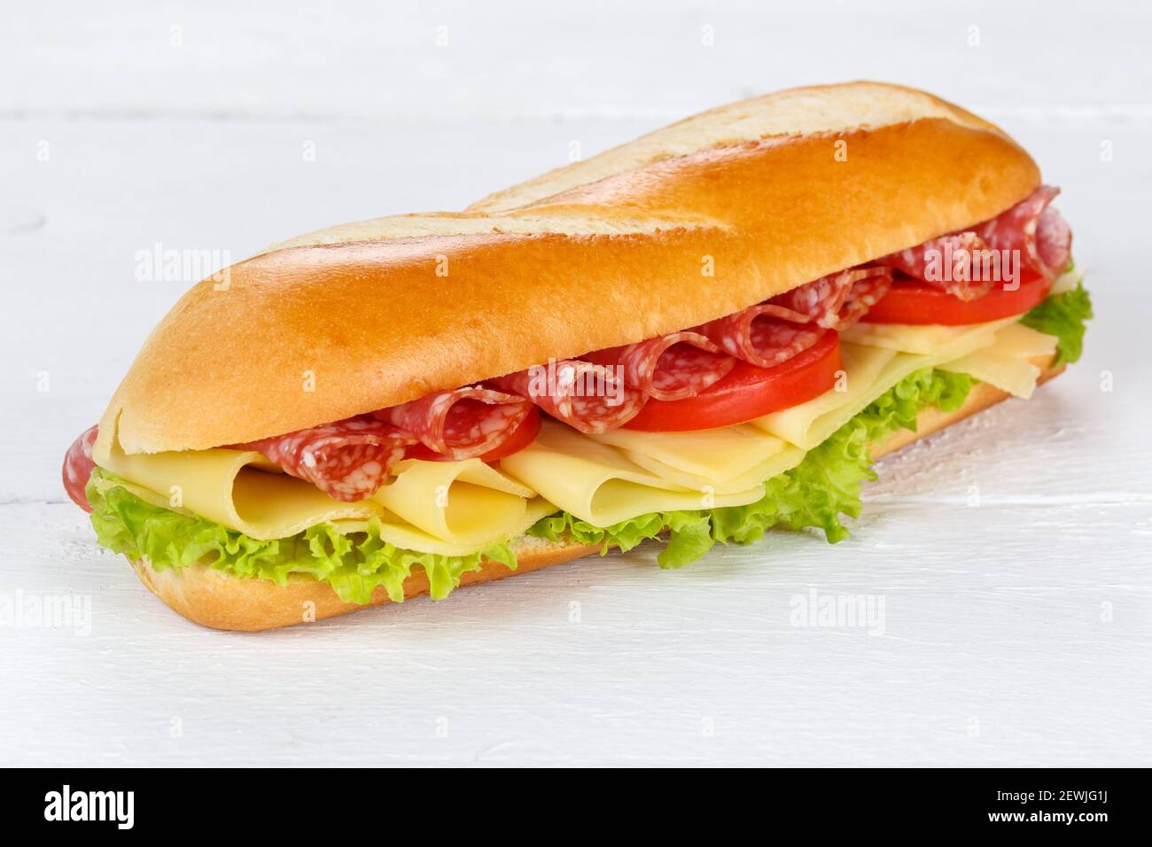 Baguette sandwich con prosciutto salame e formaggio fresco su legno di legno. Foto Stock