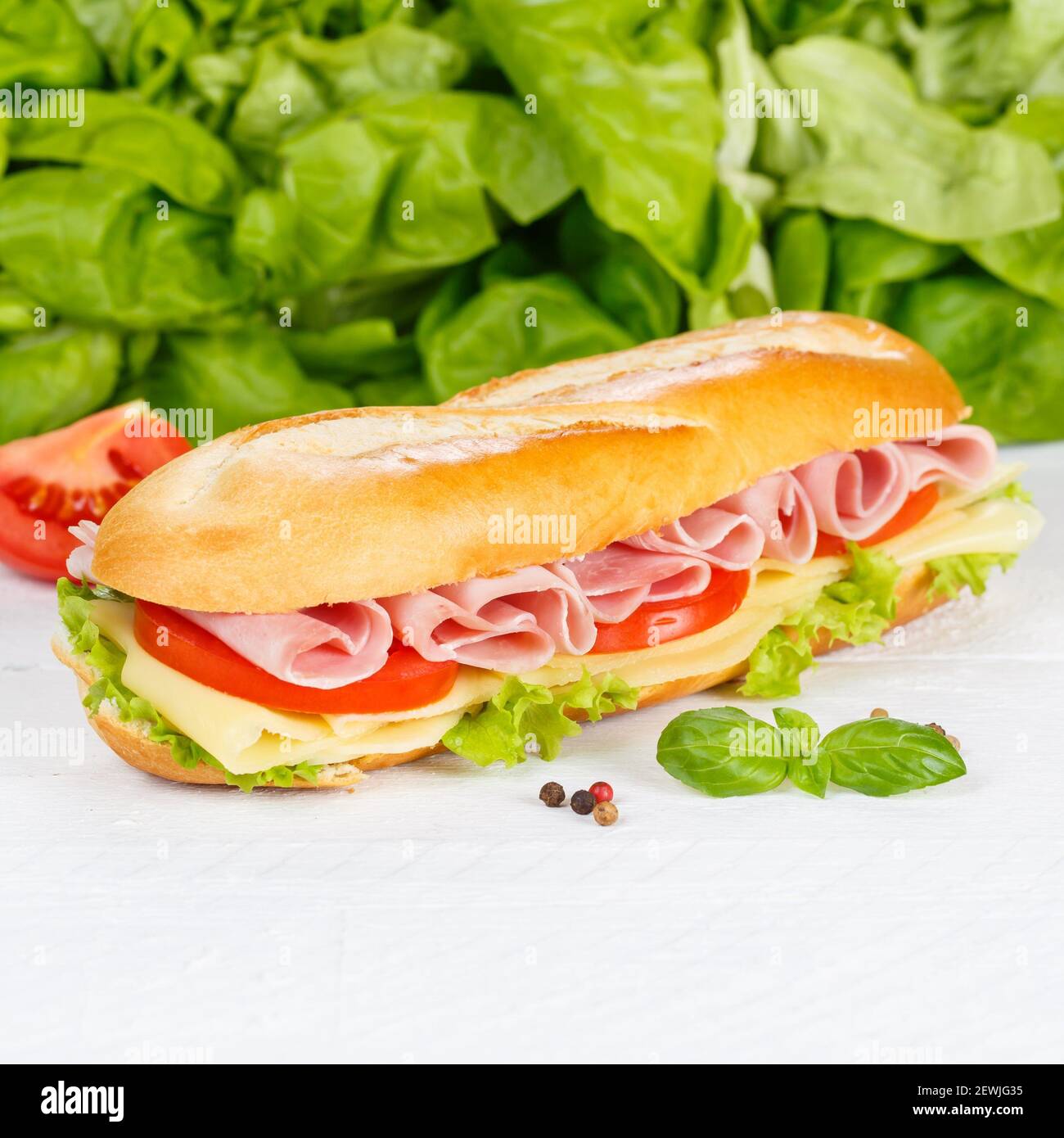 Baguette a sandwich con prosciutto e formaggio quadrato su legno di legno. Foto Stock