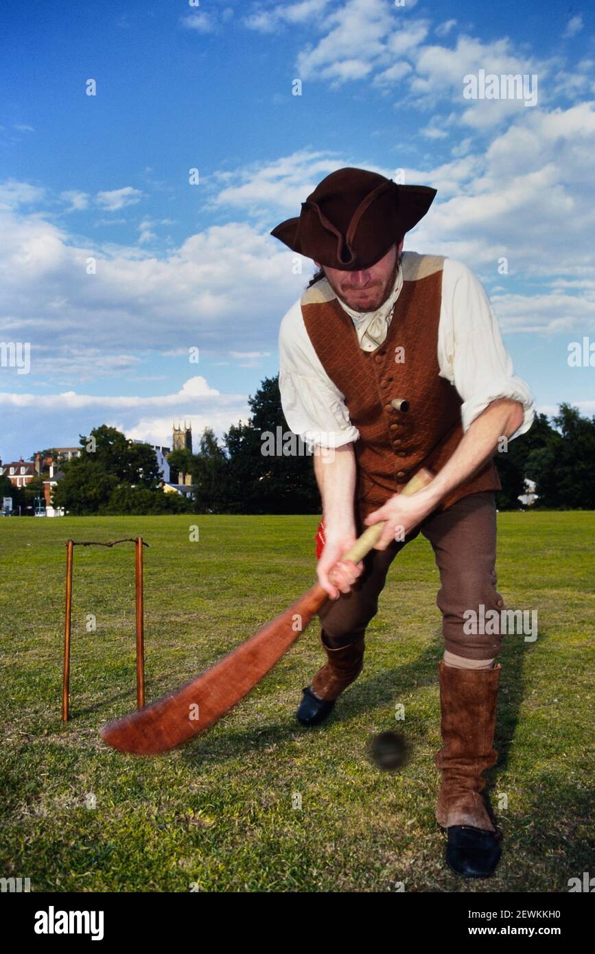 Cricketer in costume georgiano d'epoca usando un primo bat curvo di cricket. Royal Tunbridge Wells, Kent, Inghilterra, Regno Unito Foto Stock