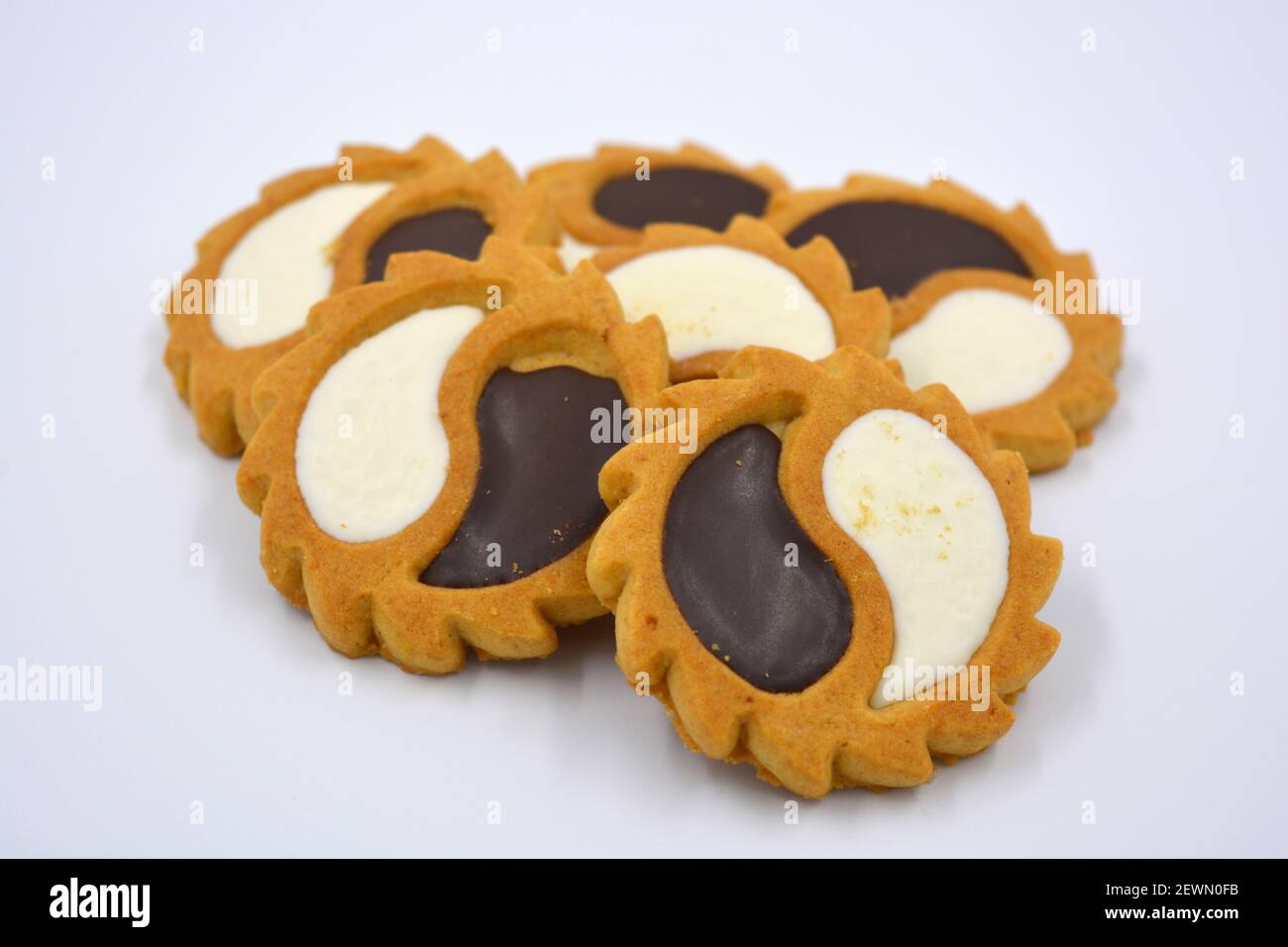Biscotto di sicurezza sotto forma di sole con stucco bianco e cioccolato, dolce sotto forma di due gocce poste su fondo bianco. Foto Stock