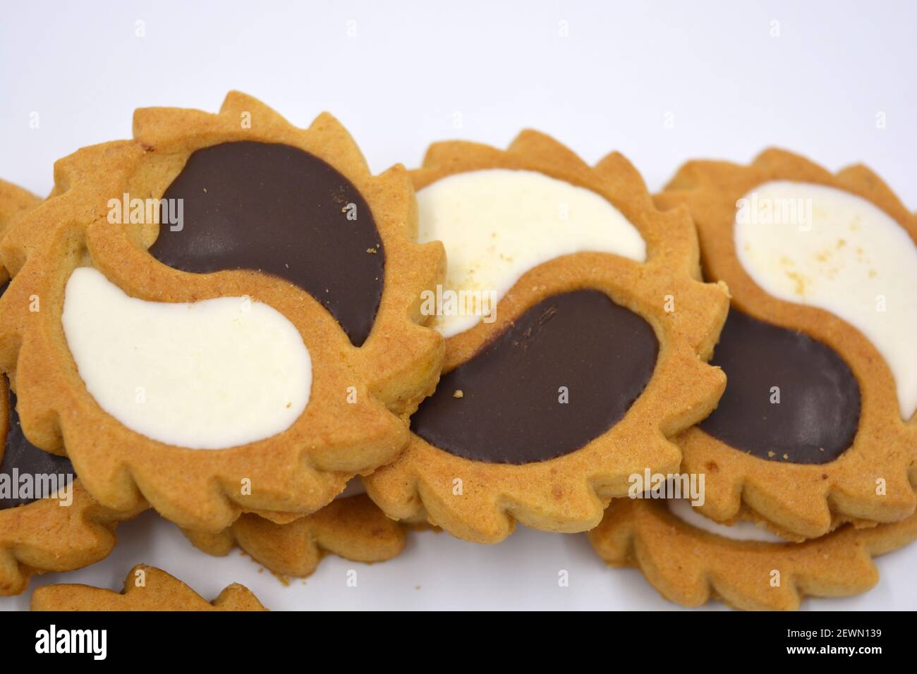 Biscotto di sicurezza sotto forma di sole con stucco bianco e cioccolato, dolce sotto forma di due gocce poste su fondo bianco. Foto Stock