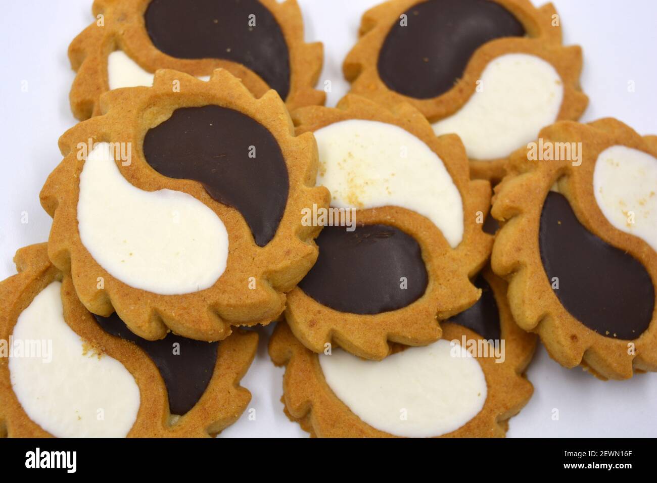 Biscotto di sicurezza sotto forma di sole con stucco bianco e cioccolato, dolce sotto forma di due gocce poste su fondo bianco. Foto Stock
