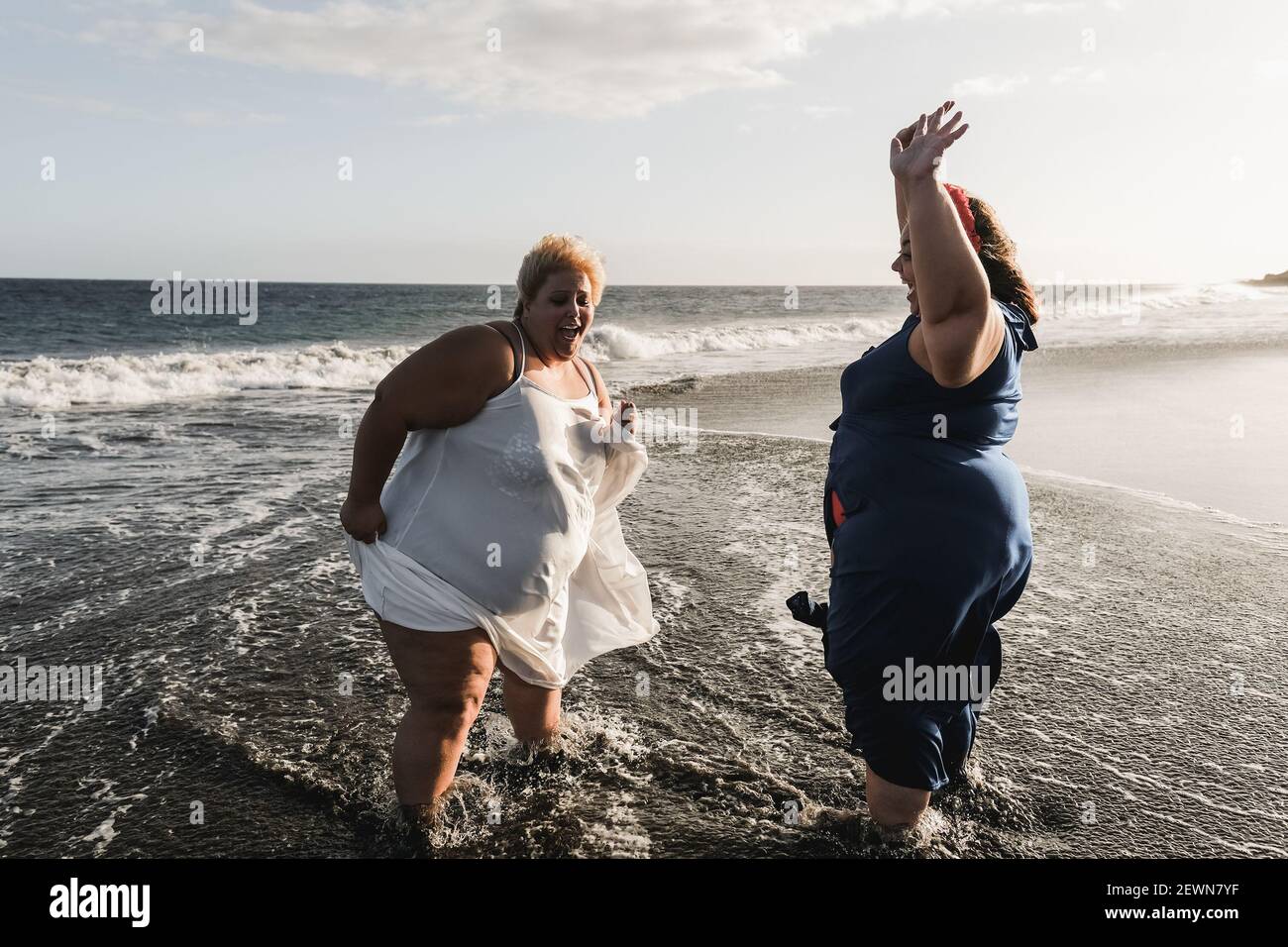 Le donne curvy ballano sulla spiaggia divertendosi durante l'estate Vacanza - Focus sulla donna sinistra Foto Stock