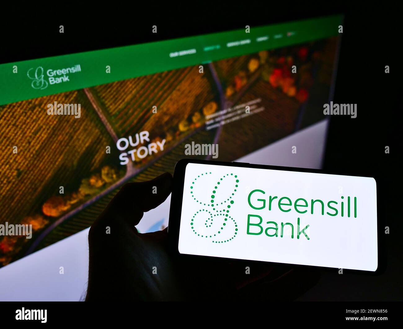 Persona che detiene smartphone con logo della società finanziaria tedesca Greensill Bank AG sullo schermo davanti al sito web. Mettere a fuoco il display del telefono. Foto Stock