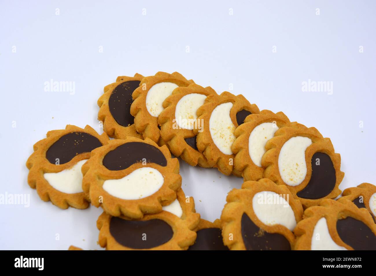 Biscotto di sicurezza sotto forma di sole con stucco bianco e cioccolato, dolce sotto forma di due gocce poste su fondo bianco. Foto Stock