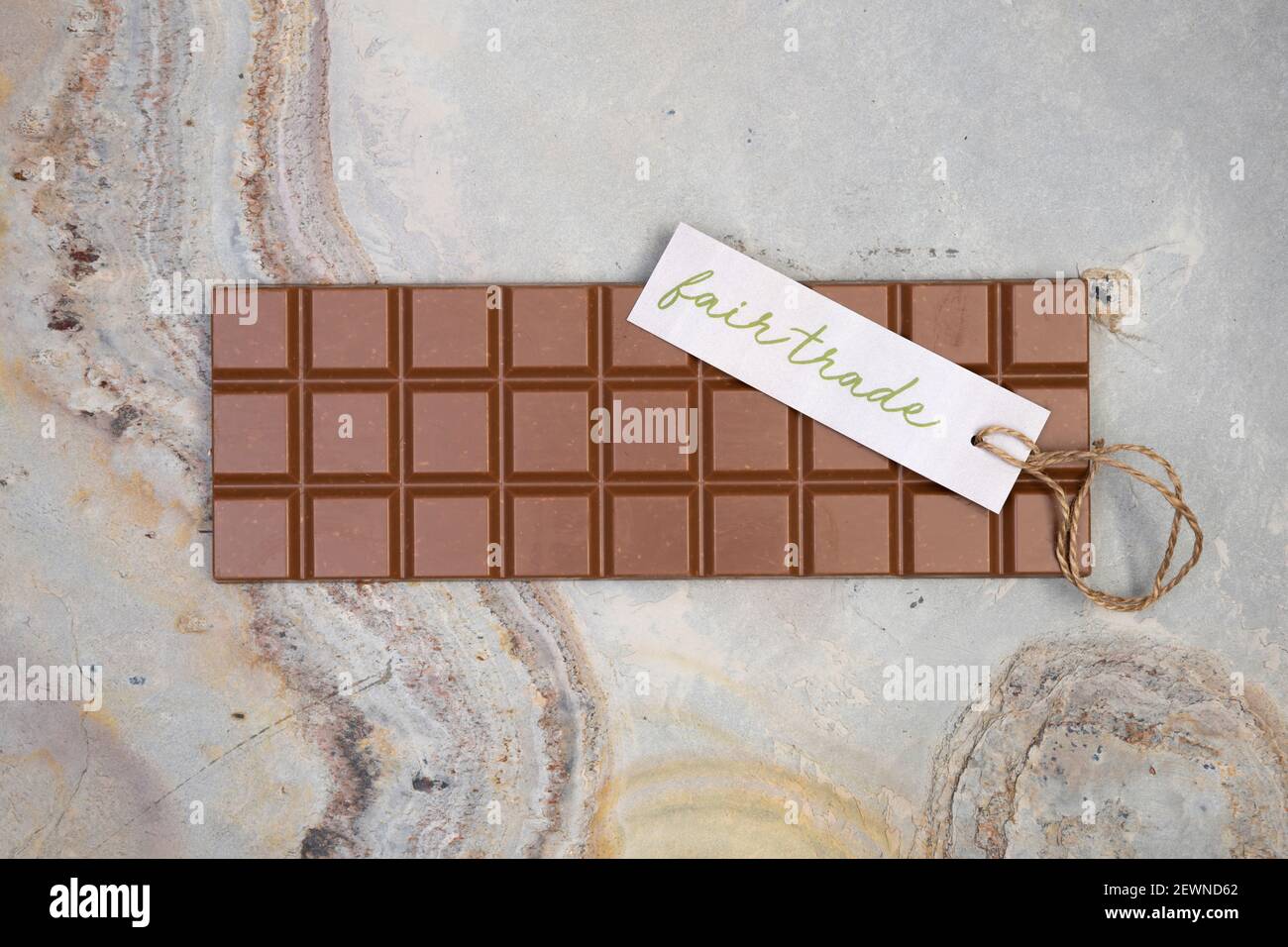 delizioso cioccolato bar intero si trova su sfondo di pietra chiaro con una piccola etichetta che dice commercio equo Foto Stock