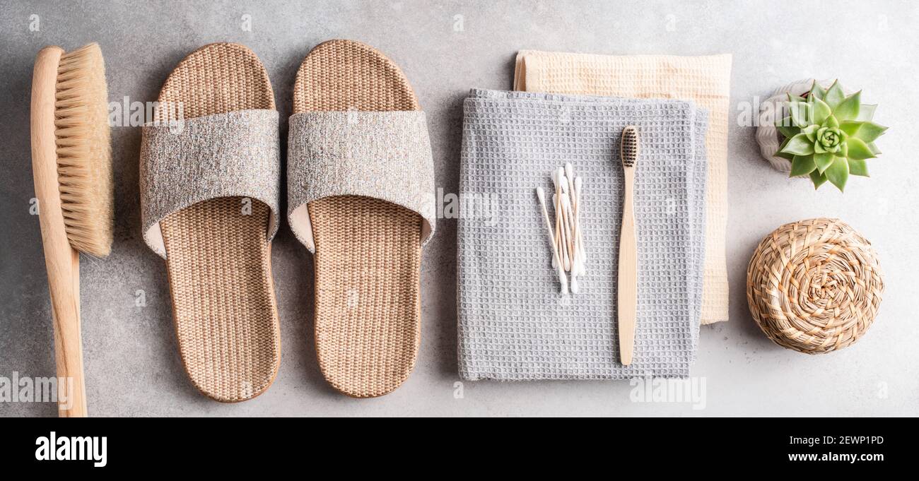 Eco spa e accessori per il bagno di bellezza su sfondo grigio in pietra. Pantofole di bambù, spazzola anticellulite, asciugamani, spazzolino da carbone, bambù ea Foto Stock